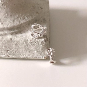 Macro shot of 925 sterling silver knotted cross earrings on a minimalist stone surface