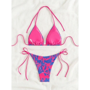Flat lay of a vibrant abstract print bikini set with pink lining on white fabric