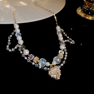 Detail of gold double-layer necklace with pearl beads and diamond heart pendant