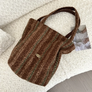 Close-up of striped faux shearling tote bag with golden brand logo on textured fabric