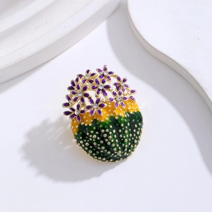 Detail of enamel cactus brooch with purple flower and crystal inlay on golden alloy base