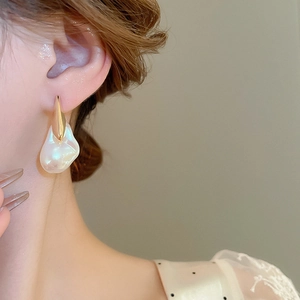 Dettaglio di orecchino pendente con perla barocca placcato oro 18K indossato da modella