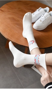 Detailed close-up of white cotton mid-calf sports socks with red and blue letter patterns