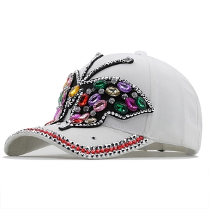 Detail of white baseball cap with colorful rhinestone butterfly and studded brim