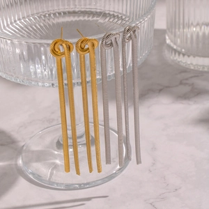 Détail de boucles d'oreilles à franges dorées et argentées sur le bord d'un verre