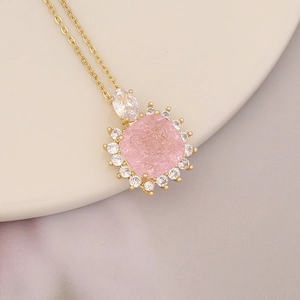 Macro shot of 18K gold necklace featuring a pink square gem and white diamond accents