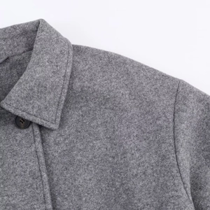 Detail view of the gray wool coat collar with a resin button and fine stitching