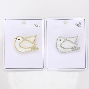 Close-up of cute shell pigeon brooches in gold and silver finish with crystal accents