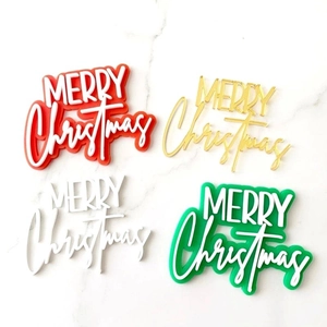 Detail showing acrylic Merry Christmas cake toppers in red, gold, white, and green finish