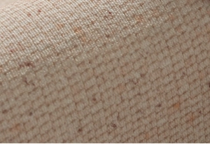 Macro view of cream woven rug texture with brown speckles and diagonal knit pattern