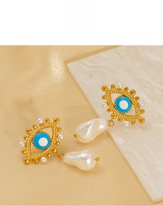 Detailed view of gold Evil Eye earrings featuring blue enamel and a hanging baroque pearl