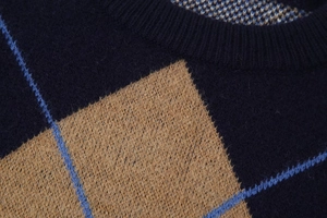 Detailed texture of navy blue knit sweater with brown and light blue diamond patterns