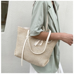 Detailed texture of straw tote bag featuring a white lace bow and leather handles