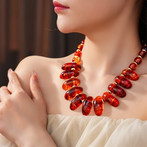 Close-up of amber oval beads and gold spacers on an irregular geometric pendant necklace