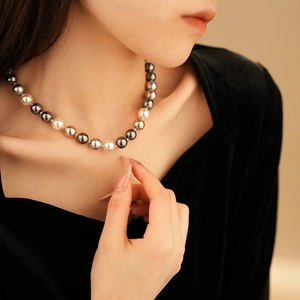 Detail of multi-color pearl necklace with white, gray, and black beads on a model's neck