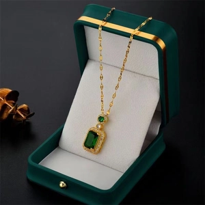 Elegant gold necklace with emerald cut green pendant in a luxury dark green velvet gift box