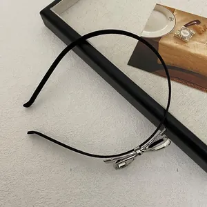 Detail of slim black headband featuring a 3D silver metallic bow on a textured background
