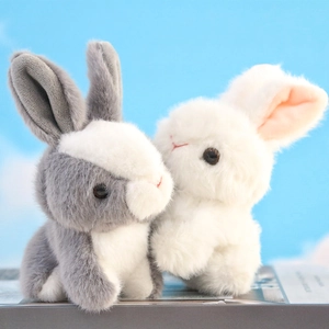 Cute plush bunny keychain set with white and grey rabbits against a blue sky background
