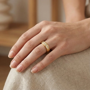 Close-up of hammered gold wedding band with small zircon diamonds on a finger