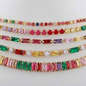 Détail de bracelets dorés avec zircons cubiques multicolores aux coupes variées