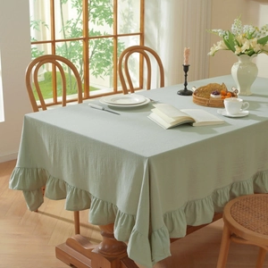 Detail of light green cotton linen tablecloth featuring decorative lotus ruffle edges