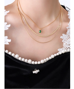Detail view of triple-layered 18K gold plated necklace with emerald green zircon pendant
