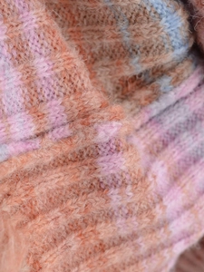 Macro shot of fluffy gradient knit fabric in orange, pink, and sky blue hues
