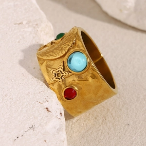Détail d'une bague large plaquée or 18 carats avec zircons colorés et gravure d'étoiles