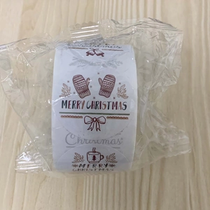 Roll of Christmas stickers with mittens and cocoa cups icons on light wood surface
