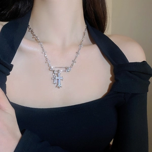 Close-up of silver pin and zircon cross pendant necklace worn by a fashion model