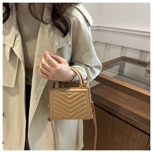 Detail of khaki quilted square handbag with V-shaped texture on chic beige trench coat
