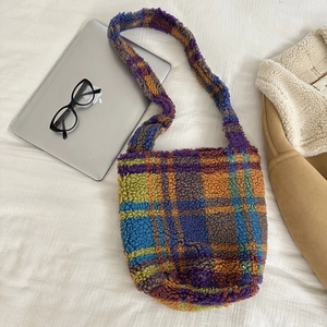 Detailed flat lay of colorful plaid plush tote bag with laptop and lifestyle props