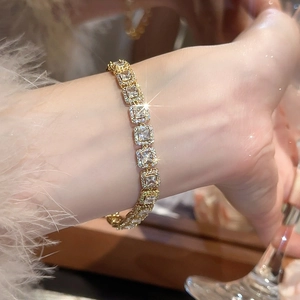 Gros plan d'un bracelet doré à maillons carrés sertis de diamants porté sur un poignet chic