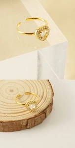 Macro detail of 18K gold-plated heart ring with sparkling zircons on a wooden base