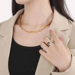 Dettaglio della collana a catena dorata OT e dell'anello multistrato con cristalli e smalto
