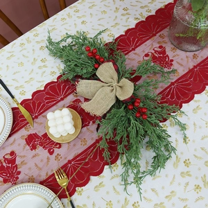 Red Christmas lace table runner featuring green pine needles, red berries and burlap bows