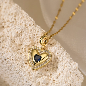 Macro shot of gold heart pendant with dark blue gemstone and tiny crystals on stone