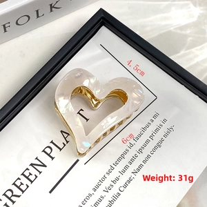 Detail of 6cm heart acetate hair claw with mother-of-pearl sheen and gold metal frame