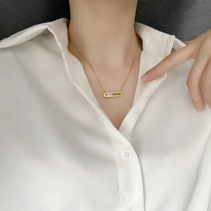18K gold plated necklace with rectangular pendant and three zircons on a white blouse