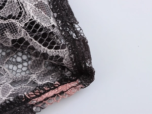 Close-up of black and pink lace fabric showing intricate mesh texture and stitching detail