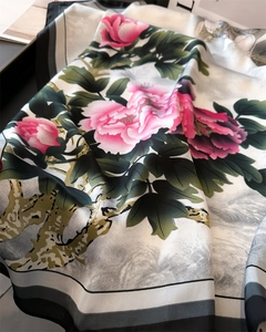 Close-up of smooth silk scarf showing pink peony floral pattern and soft fabric texture