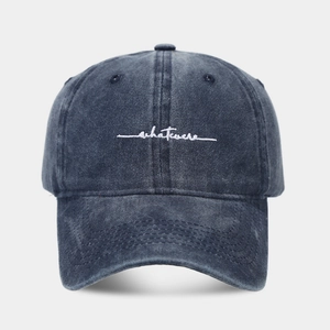 Close-up of the white Whatever cursive embroidery on a vintage grey washed cotton baseball cap