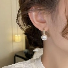 Detail of rose gold pearl earrings with zircon accents on a female model side view
