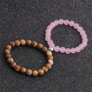 Detail of beaded magnetic couple bracelets with pink and brown stones on dark glitter