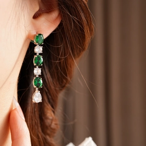Gros plan de boucles d'oreilles pendantes avec pierres vertes et claires sur un modèle