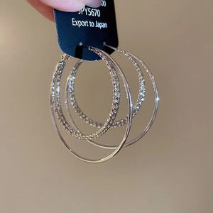 Close-up of silver-plated multi-layer hoop earrings with textured and smooth finishes