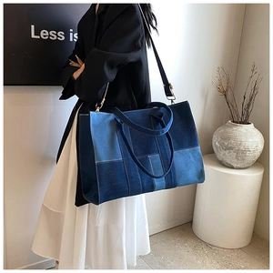 Detail of a large denim patchwork tote bag with adjustable shoulder strap and double handles
