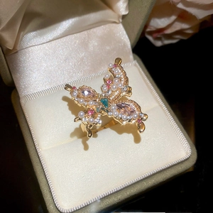 Detailed close-up of a butterfly ring with colorful crystals and pearls in a velvet jewelry box