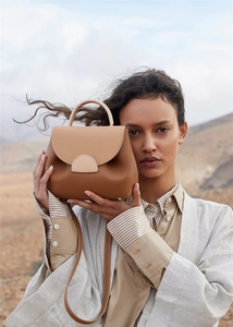 Detailed view of bicolor leather handbag with top handle and flap in desert setting