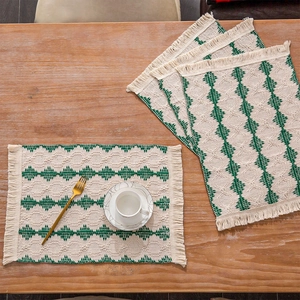 Detail of woven table mat with green geometric patterns and fringed tassel edges
